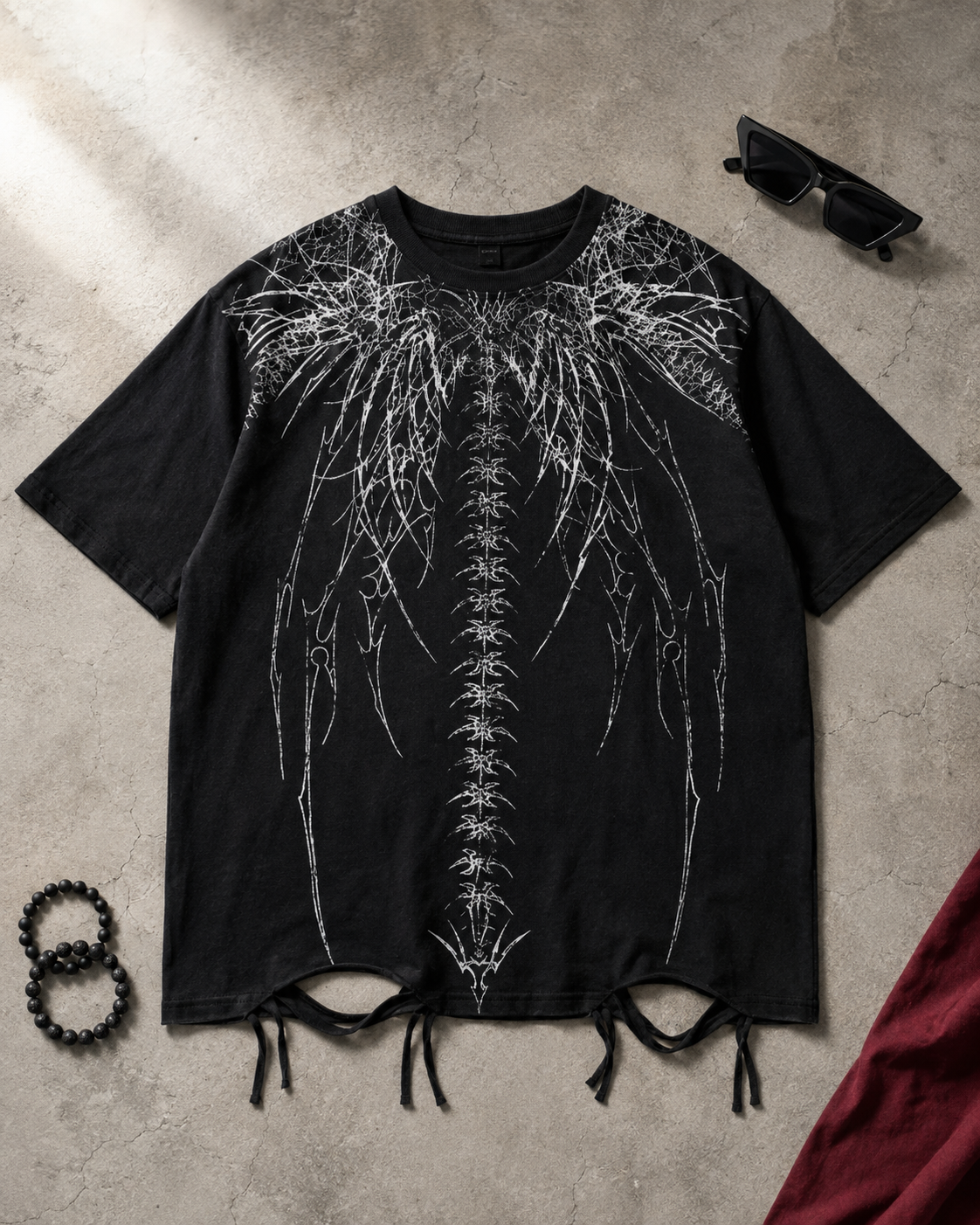 Flat lay of the black Spine Graphic Streetwear T-Shirt with distressed tie hem